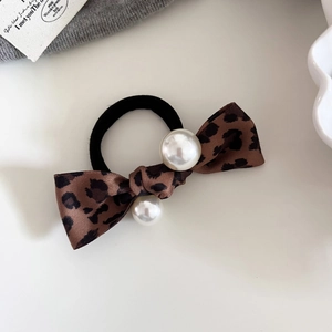 Macro detail of leopard print bow hair tie featuring glossy white pearls and elastic band