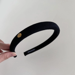 Detail of black striped knitted headband with gold logo tag and handmade label