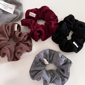 Detail view of four knit scrunchies in burgundy, coffee, black, and gray with Hand Made tags