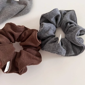 Close-up of knit scrunchies in brown and grey with visible Hand Made fabric labels