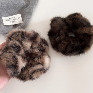 Detail view of plush leopard print and solid brown faux fur scrunchies for hair styling