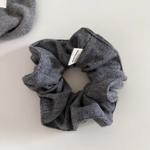Detail of soft gray knitted scrunchie texture with a decorative Hand Made woven label