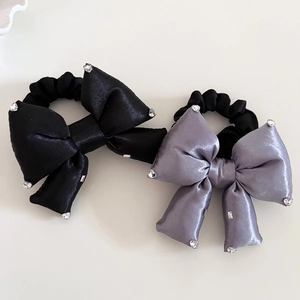 Détail de chouchous en satin avec nœud et strass étincelants en noir et gris argenté