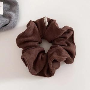 Macro shot of brown ribbed knit scrunchie texture with a white Hand Made textile label