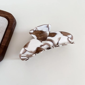 Detailed close-up of marble pattern acetate shark clip with golden French lettering