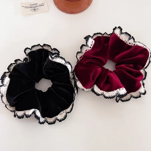 Detail of velvet hair scrunchies with white lace trim in black and wine red colors