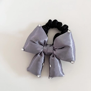 Chouchou en satin gris avec nœud, strass et élastique noir sur fond blanc neutre
