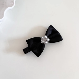 Détail de la barrette nœud en satin noir avec fleur en perles et pince à bec de canard