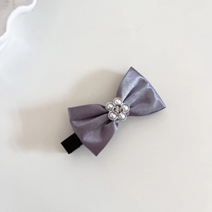 Détail d'une pince à cheveux en satin argenté avec fleur en perle et barrette crocodile