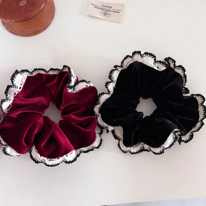Close-up of velvet scrunchies with white crochet lace edges in black and burgundy red