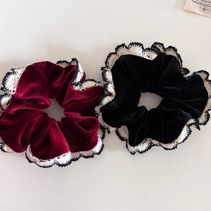 Detail of red and black velvet scrunchies with white lace crochet edges and soft texture