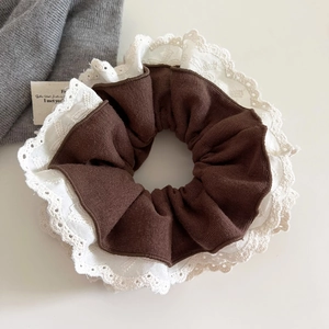 Detailed close-up of dark brown ribbed fabric scrunchie with white lace floral trim