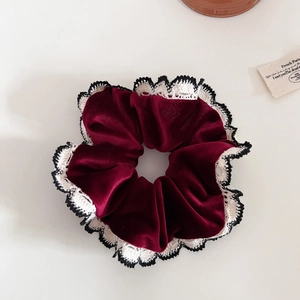 Detailed close-up of dark red velvet scrunchie with crochet lace edge craftsmanship