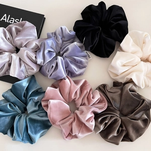 Dettaglio di sette elastici per capelli in velluto in vari colori su una scrivania neutra