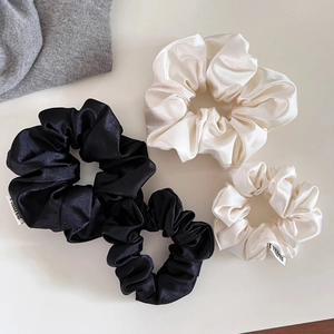 Détail de chouchous satinés haut de gamme en noir et crème avec texture soyeuse lisse