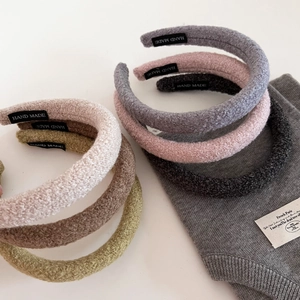 Close-up of thick textured wool headband collection with handmade label and soft colors