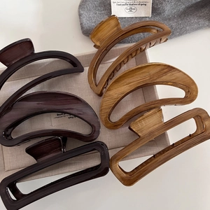 Detail view of wood grain claw clips in amber and brown tones with hollow designs