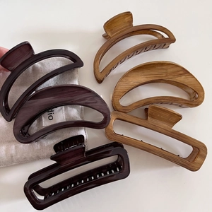 Set of large wood-grain finish hair claws in purple and caramel with a gray cloth bag