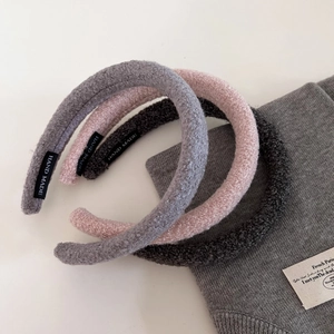 Detailed view of handmade plush lamb wool headbands in pink, light grey, and charcoal grey