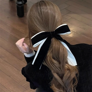 Detail view of large velvet and satin bow hair clip worn in a half-up hairstyle