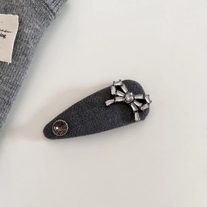 Dettaglio fermaglio per capelli in maglia grigio scuro con fiocco di strass e gemma