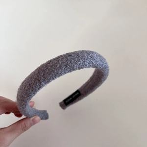 Detailed macro view of the grey lamb wool texture and handmade label on a thick headband