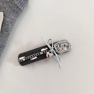 Dettaglio del fermaglio in tweed grigio con catena argento e ciondolo a cuore