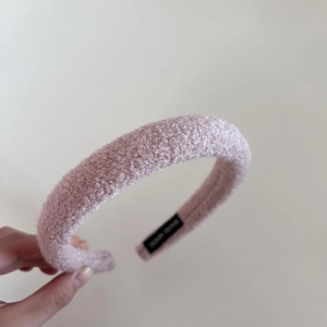 Close-up of pink lamb wool headband with visible grain texture and Hand Made woven label