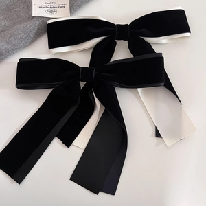 Detail of elegant black velvet hair bow with white satin lining and spring clip