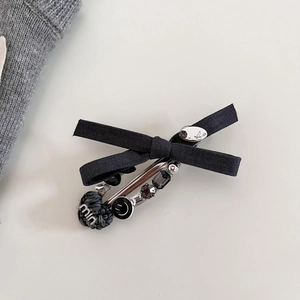 Dettaglio della clip a spilla con cuore grigio, fiocco nero e cristalli sfaccettati