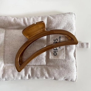 Close-up of a large brown wood-grain hair claw with a minimalist half-moon shape