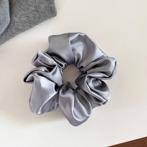 Vue détaillée d'un chouchou en satin gris argenté avec une texture plissée élégante
