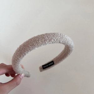 Detailed macro view of beige teddy fleece headband with a sewn HAND MADE label