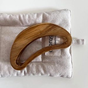 Detailed close-up of large semicircular wood grain hair claw clip with glossy finish