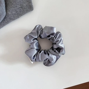 Détail rapproché d'un chouchou en satin gris argenté avec texture verticale et couture fine
