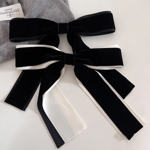 Detail of elegant black velvet hair bow with white satin lining and long ribbons