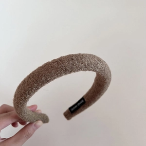 Close-up of brown lamb wool headband with handmade label showing soft fleece texture