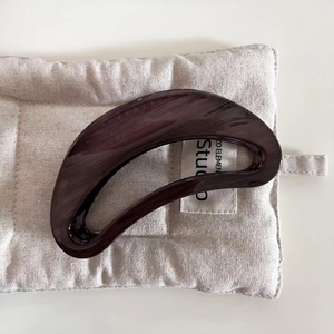 Close-up of semi-circular hair claw clip with dark brown marble grain and glossy finish