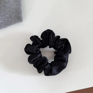 Gros plan d'un chouchou élégant en satin noir avec texture en soie et détails plissés