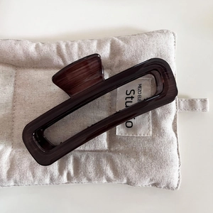 Detail view of large dark brown wood texture hair claw clip on beige quilted mat