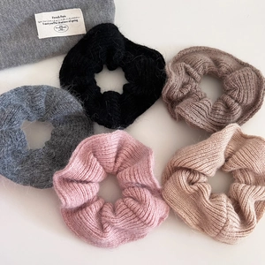 Detail showing five different colors of soft knitted scrunchies with wool textures