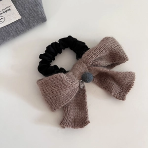 Chouchou élégant en maille avec nœud papillon, pompon et pendentif sourire sur fond blanc