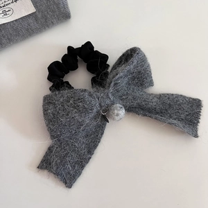 Gros plan d'un élastique à nœud en tricot gris avec détails en soie et pompon