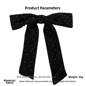 Detail view of large black bow hair clip with white sequins and a 10cm spring clip