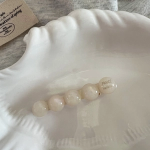 Détail macro d'une barrette fait main en perles marbrées dans un plateau coquillage