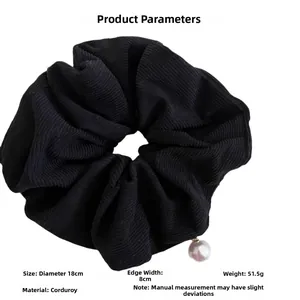 Macro shot of large black corduroy scrunchie with pearl charm and dimension specs