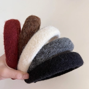 Detail of five wide-brimmed wool felt headbands in deep red, brown, white, gray, and black