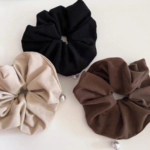 Three corduroy scrunchies in black, cream, and coffee brown with pearl charms