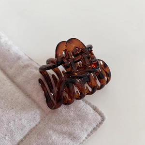 Close-up of tortoise shell pattern hair claw clip on neutral linen texture background