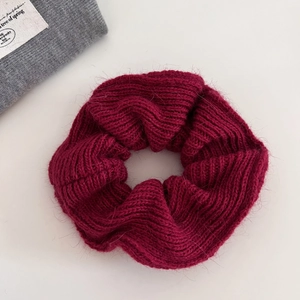 Detailed close-up of a burgundy knit scrunchie showing soft wool texture and patterns